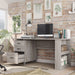 Left angled transitional coastal white office desk with three drawers and one open in a home office with accessories