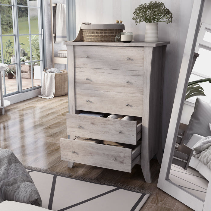 Left angled transitional coastal white five-drawer tall dresser with splayed legs and two drawers open in a bedroom with accessories