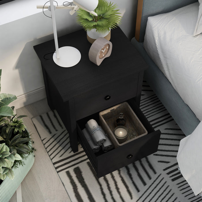 Right angled top view transitional two-drawer black nightstand with lower drawer open in a bedroom with accessories