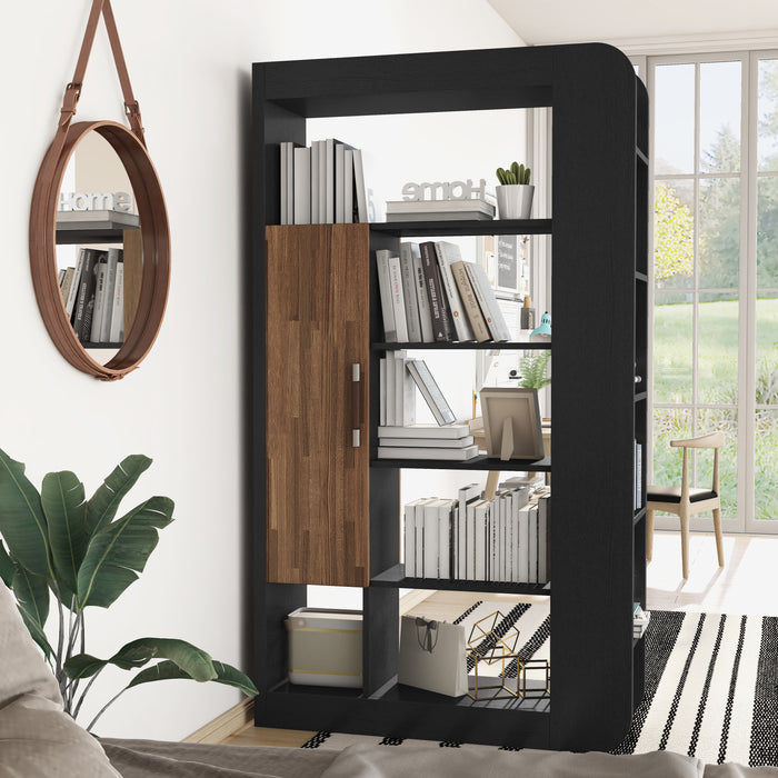 A bookcase juts out from the wall in a contemporary studio to display books, decor, and plants. Behind the bookcase is a chair and in front is a circular mirror hanging on the wall. Below it is a palm tree.