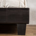 Front-facing, detail shot of the brown faux crocodile leather footboard and tapered black feet.