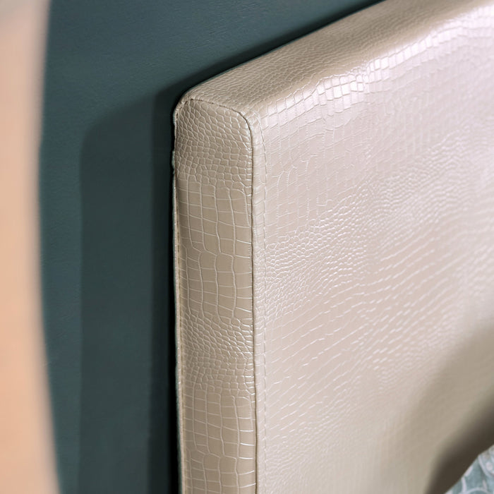 Right-angled, detail shot of the pearl white faux crocodile leather queen headboard in a contemporary bedroom. A slight gold sheen reflects off the upholstery.